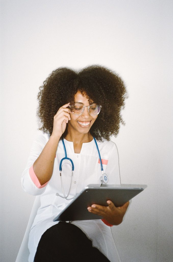 A smiling healthcare professional with a stethoscope and tablet