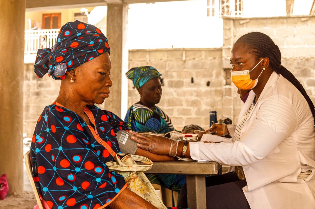 A healthcare professional checking an older woman’s blood pressure at a community health outreach